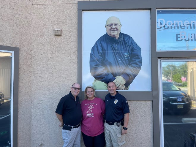 Jay Pew, senior director of the facilities at Burlington Stores (left), Burlington Township Food Pantry founder Carol Zulla (center) and Burlington Township police officer Eric Pew are shown in front of the food pantry. Eric Pew is Jay Pew's son. Burlington Stores spearheaded a major renovation at the food pantry. (Zulla's late husband Domenic is shown in the background picture).